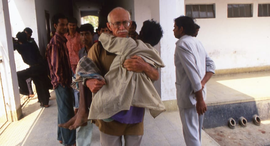 Father Bob McCahill, M.M. carrying a patient to the hospital (Bangladesh)