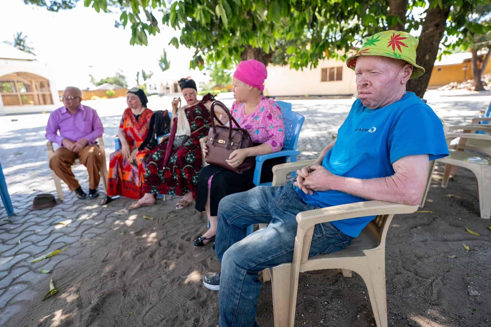 A group of people who have albinism sit outside under the shade of a tree in Tanzania
